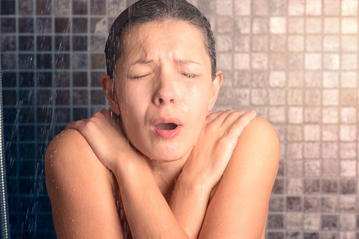 Woman shivering under a cold shower - needs an expert in hot water repairs