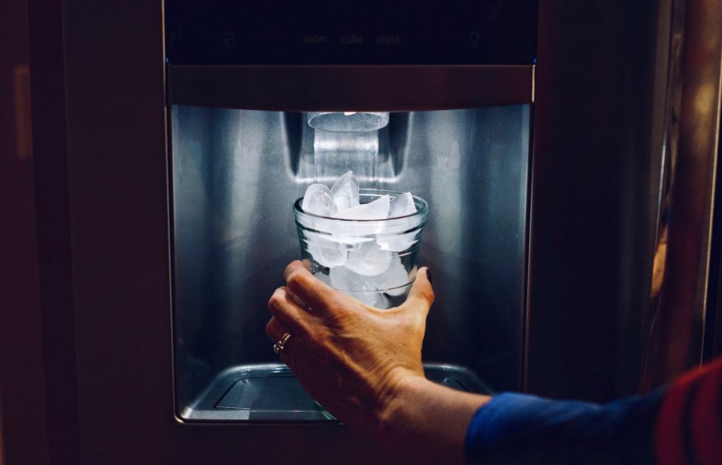 Ice and water dispenser filling a glass on a plumbed in fridge - to install a water connected fridge use reliable plumbing services. Brisbane plumbers Salmon Plumbing can help. 