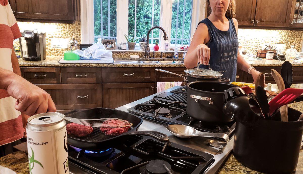 Couple cooking food on gas stove in kitchen