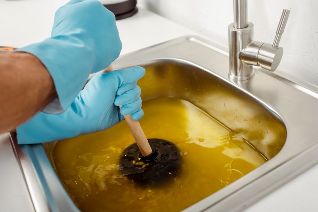 Man using a plunger to unblock a sink drain