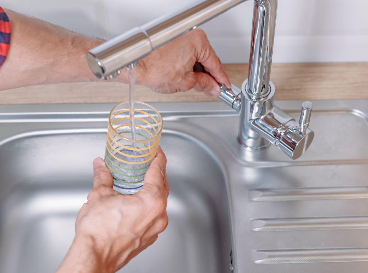 Filling glass with drinking water from tap - a water filter system will help eliminate contaminants